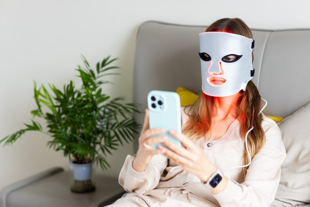 woman using led light therapy face mask and smartp 2026 05 05 19 29 19 utc